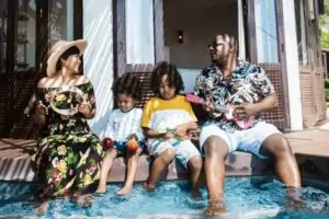 Cheerful family on vacation sitting in pool holding instruments.
