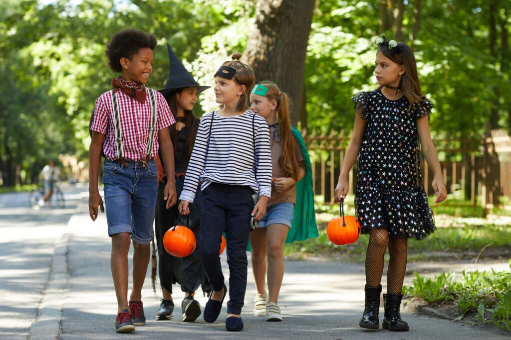 Group of children walking dressed in Halloween costumes.