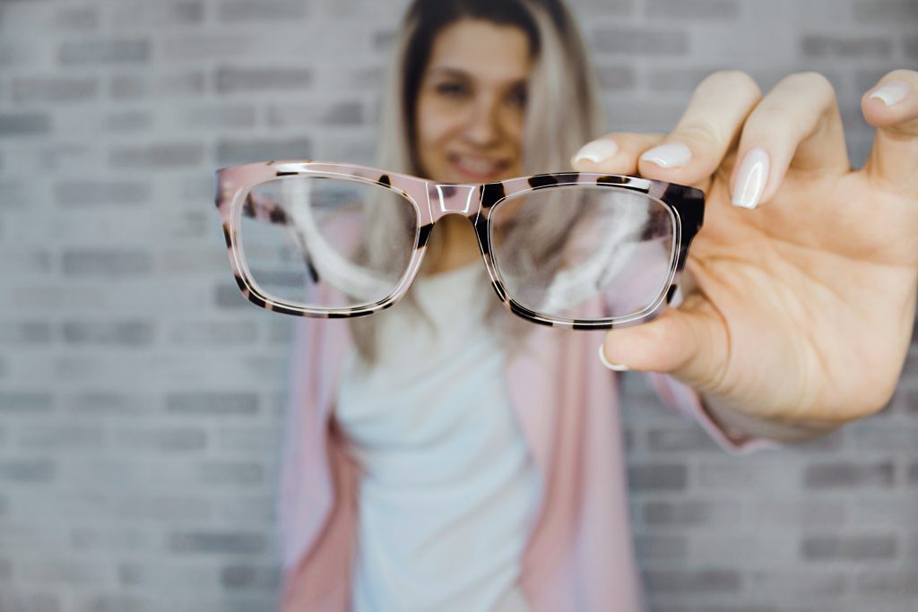 Person holding out their glasses in front of them.