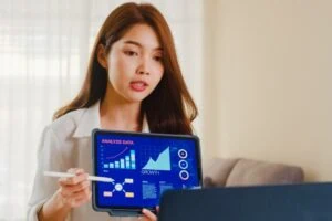 Asian person presenting information on tablet.