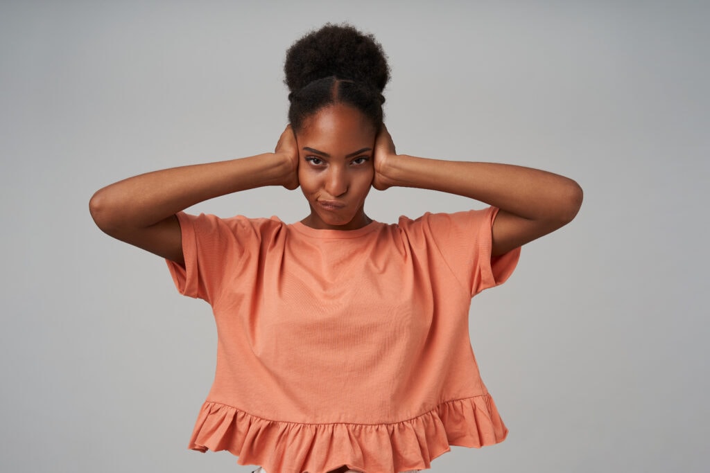 Woman standing covering her ears from sensory overload.