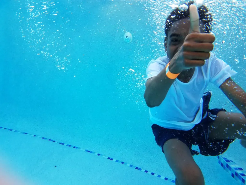 Child swimming underwater giving a thumbs up.