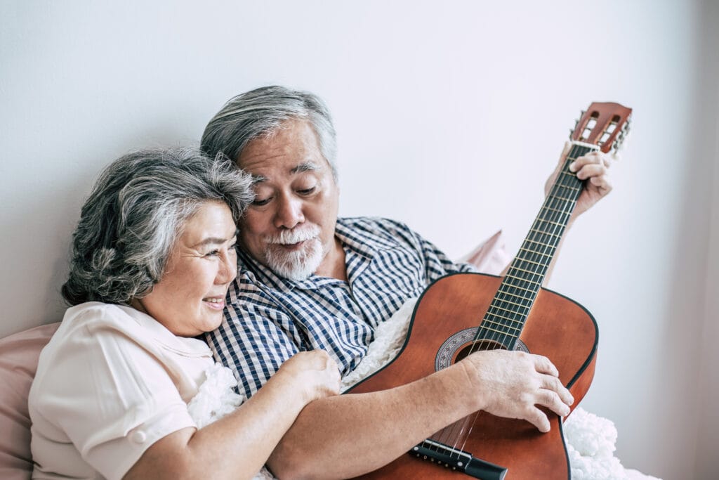 Senior couple relax playing acoustic guitar in bed room