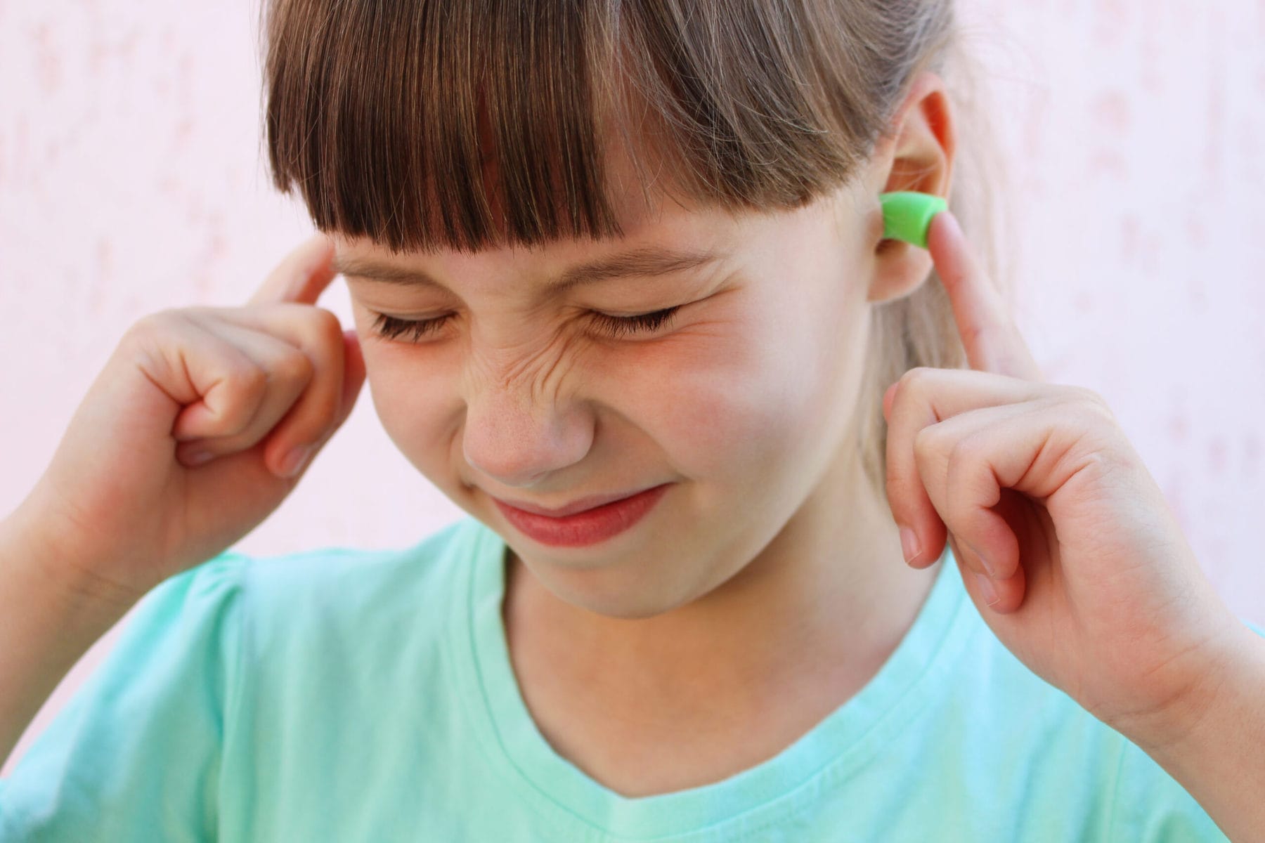 Person with ear plugs to protect against sensory overload and noise.