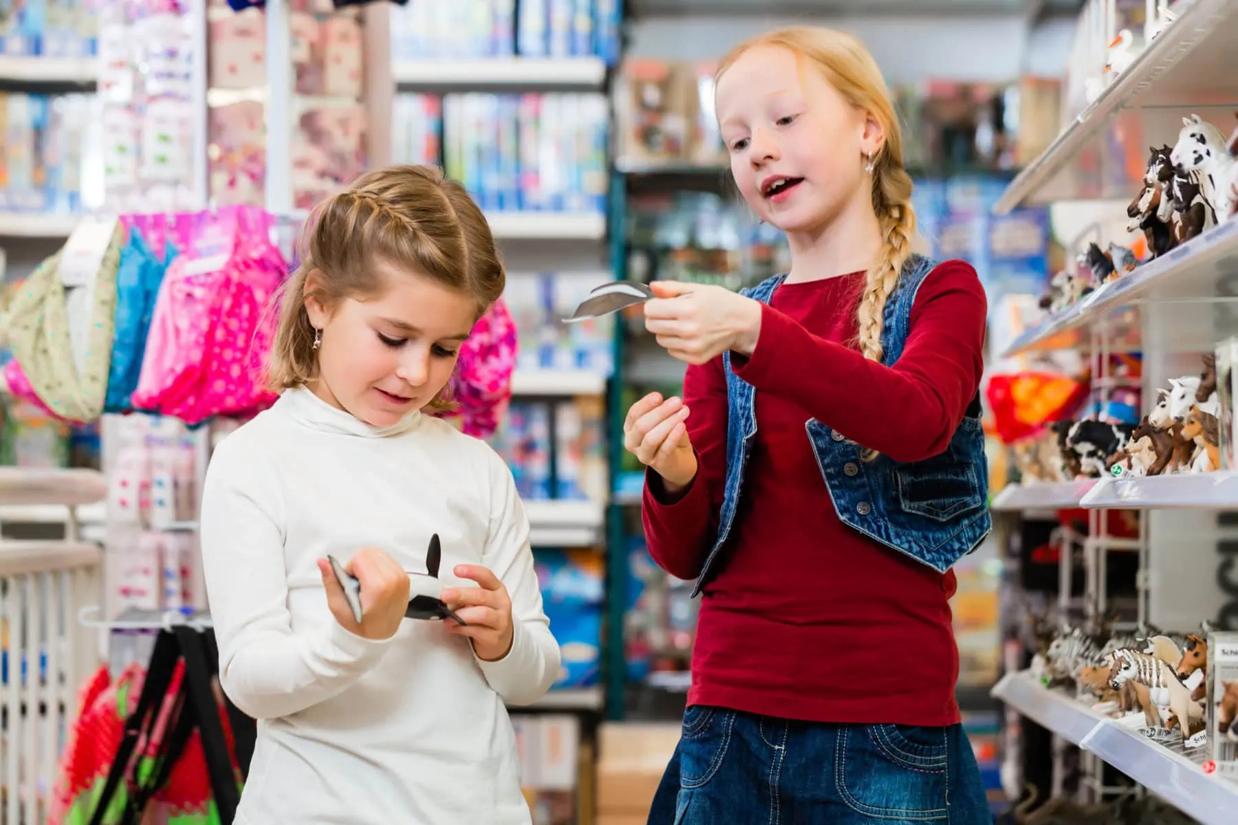 Two kids buying toys in toy store close to a shelf with figures
