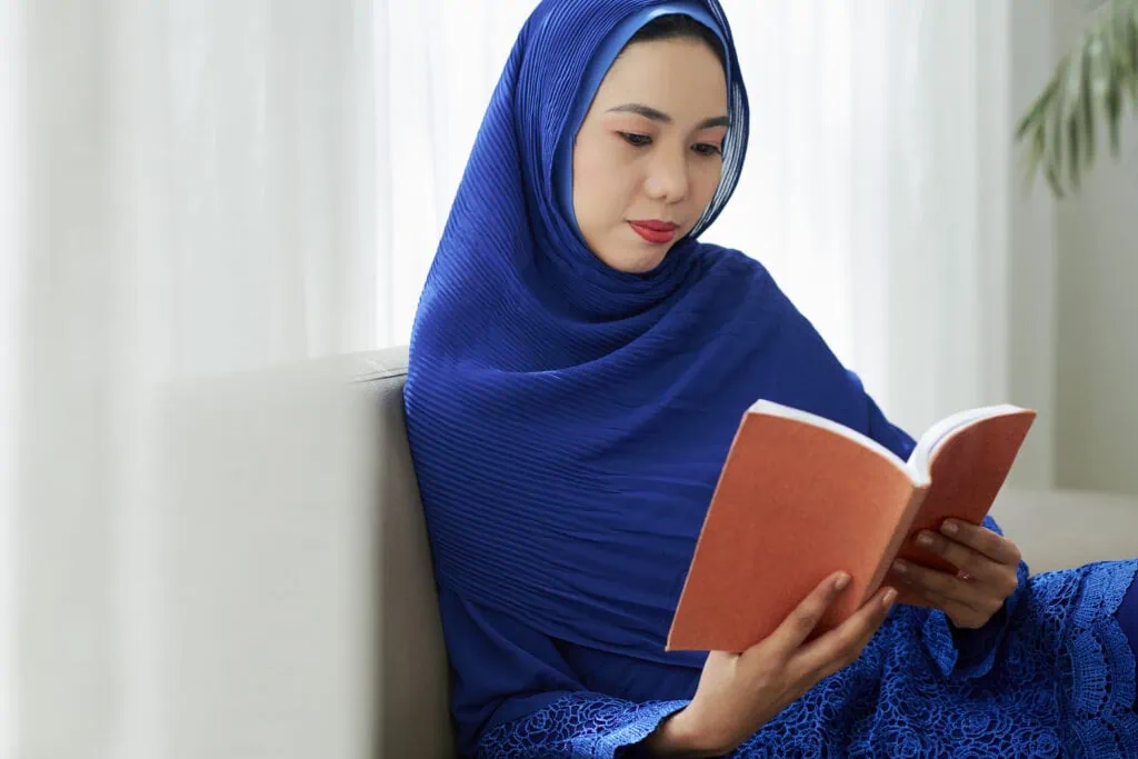 Asian woman in hijab reading a book 