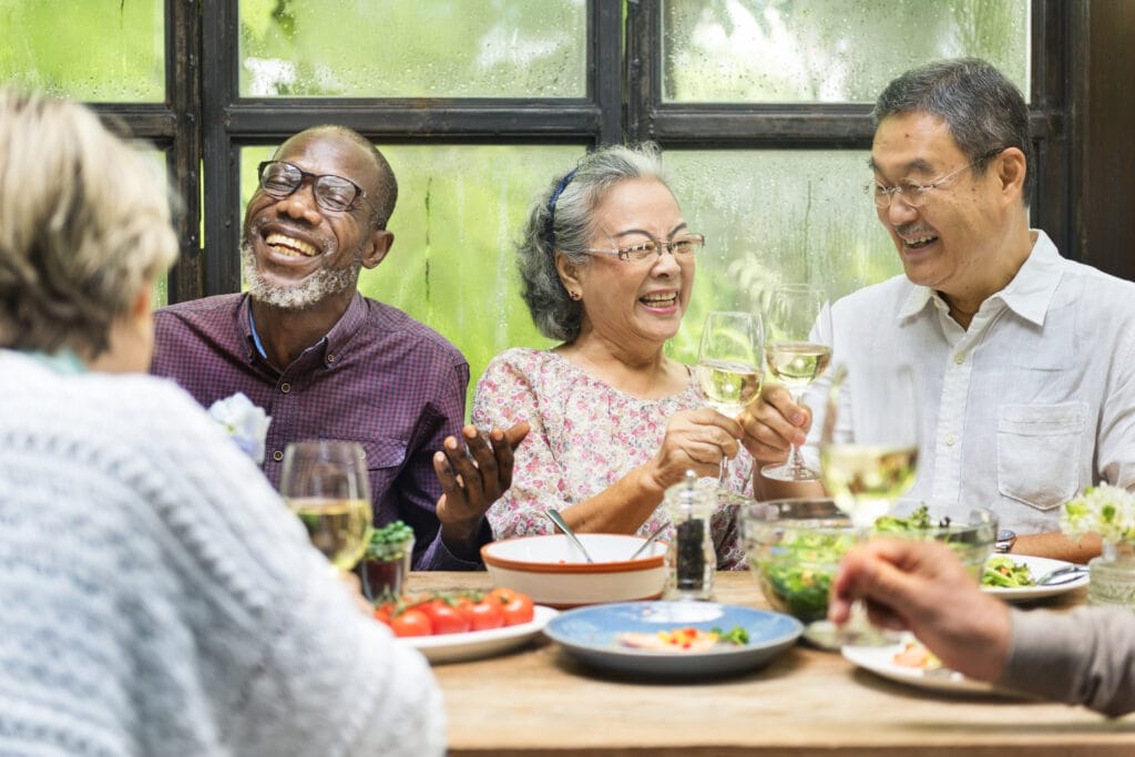 Group of adults at dinner table drinking wine.
