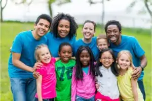Smiling, diverse group of children and adults at a sensory-friendly camp.