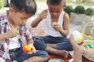 Two young children sitting on blanket painting Easter Eggs.