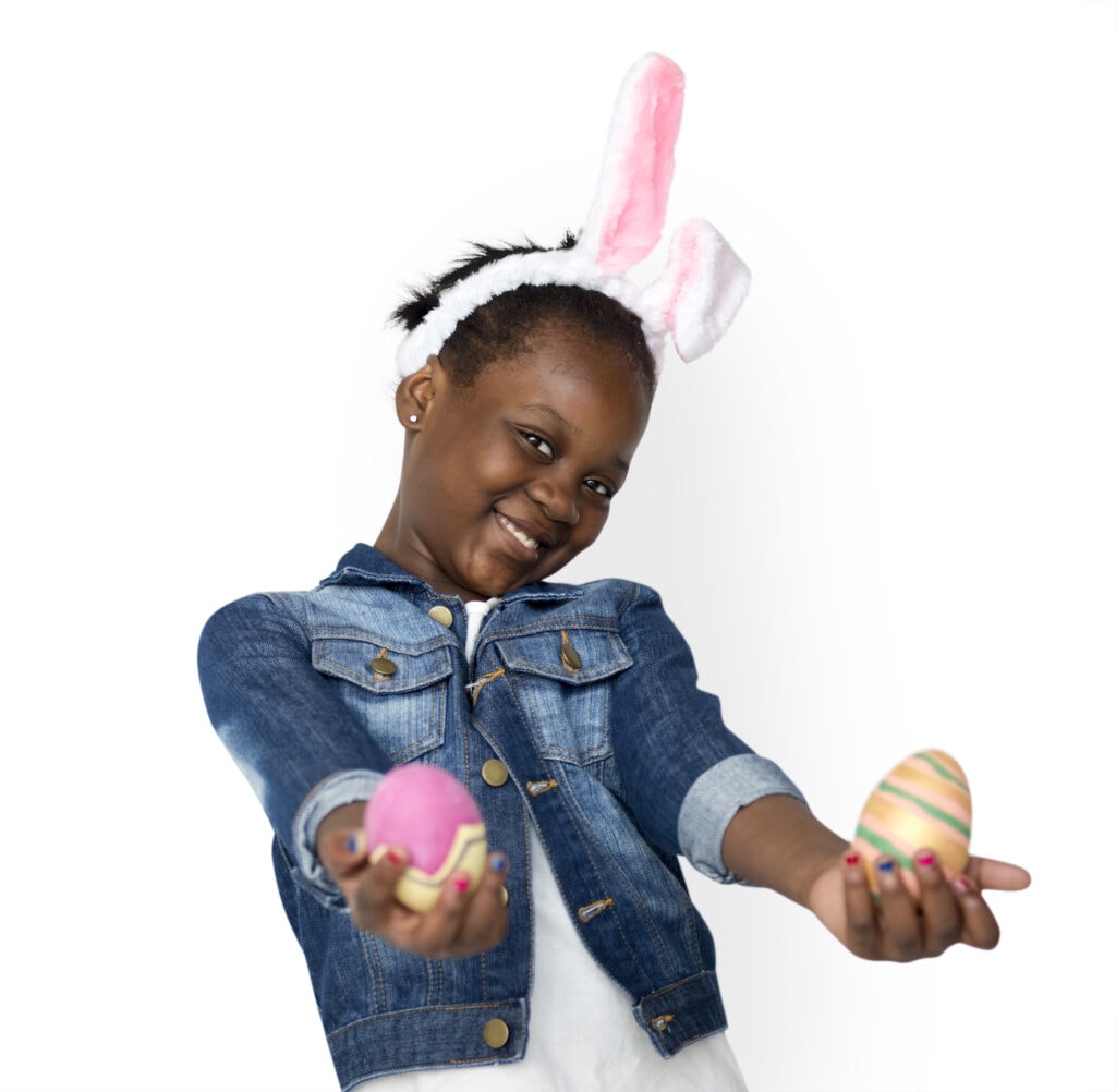Little girl holding out Easter eggs smiling at camera.