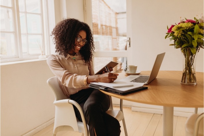 Young person sitting at table on their laptop in a meeting.