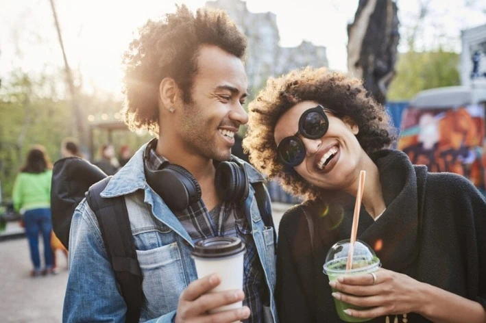 Young couple holding cups at an outdoor sensory-friendly event.