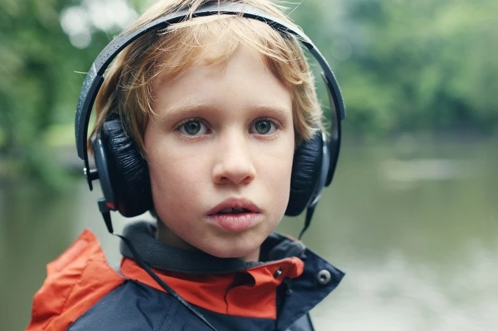 Young boy wearing noise-cancelling headphones for autism