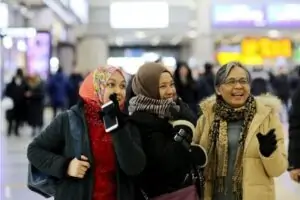 A woman her two daughters standing in a busy airport.