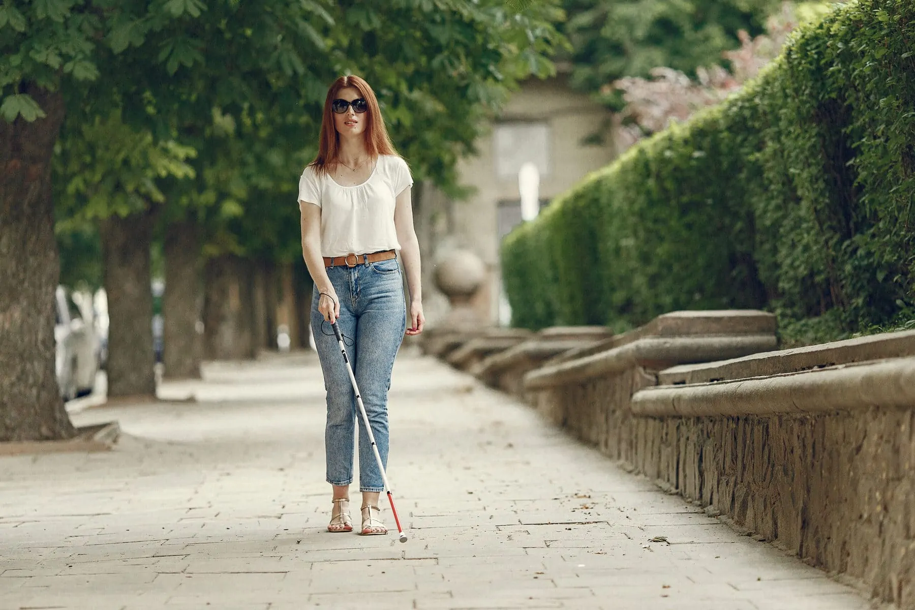 Young blind person walking with cane visual aid.