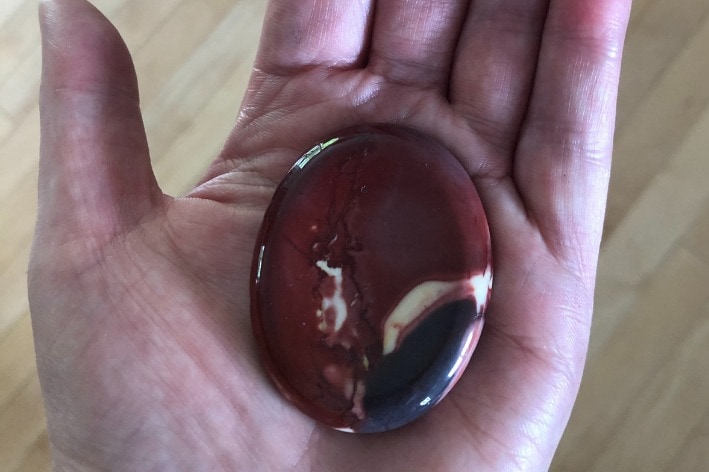 Woman's hand holding a brown focus stone.