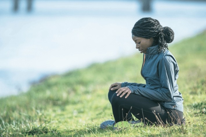 Person sitting by the water meditating to reduce sensory overload. 