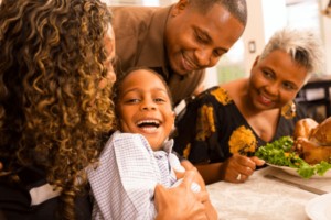 Family smiling at dinner table during sensory-friendly Thanksgiving.
