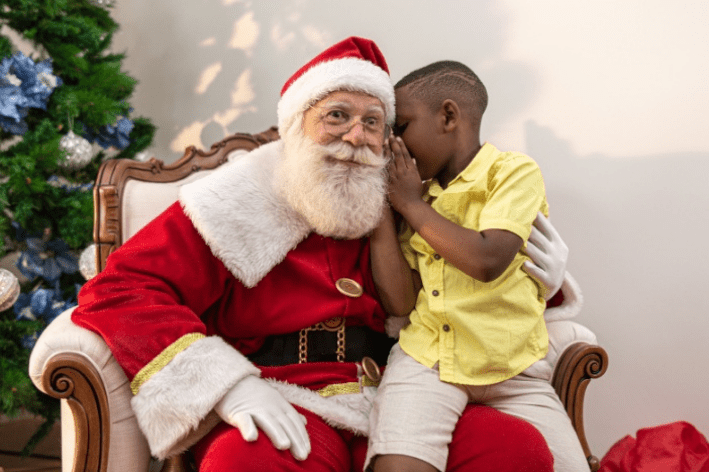 Young person sitting on Sensitive Santa's lap whispering into ear.