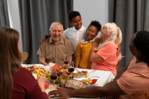 Grandparents and grandchildren gathered around the Thanksgiving dinner table smiling.