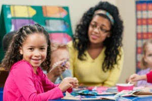 Teacher sitting with students working on sensory-friendly Valentine's Day craft.