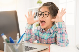 Young person sitting at desk in front of computer making a silly face during sensory-friendly Valentine's Day party..