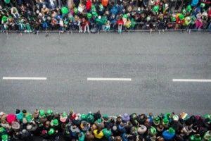 St. Patrick's Day street parade with crowds of people on either side of the street.