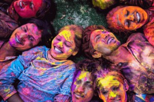 Multiple people laying together on the floor with colourful powder on them.