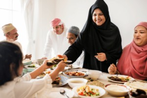 Muslim family gathered around dinner table at sensory-friendly Iftaar party.