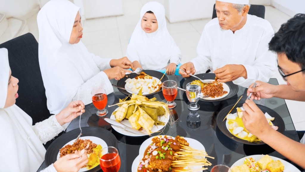 Muslim family gathered around a dinner table at a Iftaar party. 