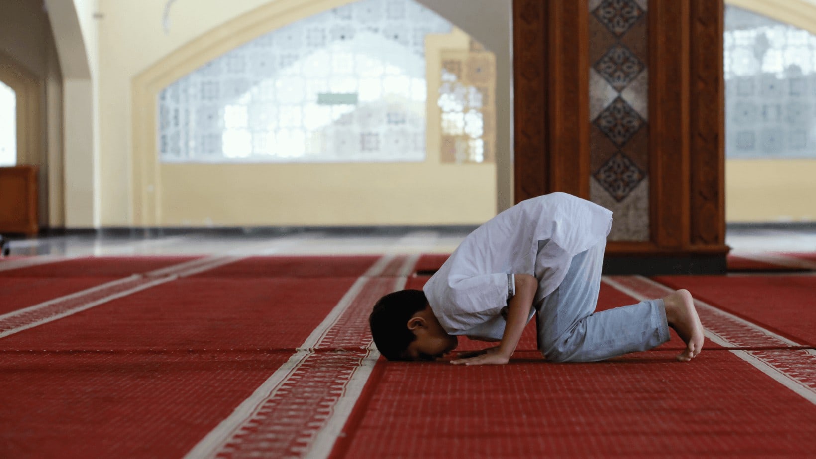 Young boy praying in sensory-friendly mosque.