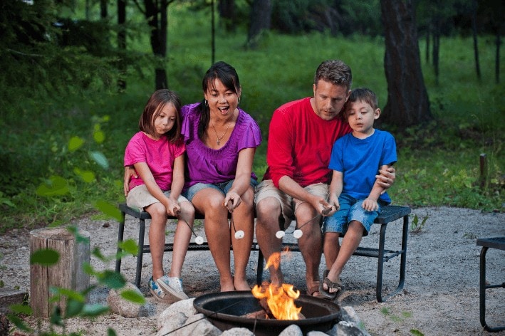Young family sitting around a fire pit at a sensory-friendly campsite.
