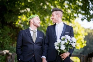 Two grooms smiling at each other at their sensory-friendly wedding.