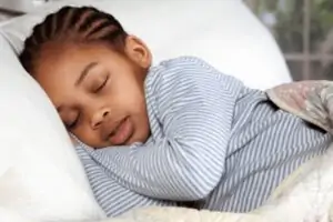 Young kid sleeping in bed with weighted blanket.