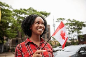 Woman holding Canada Day flag standing outside on street.