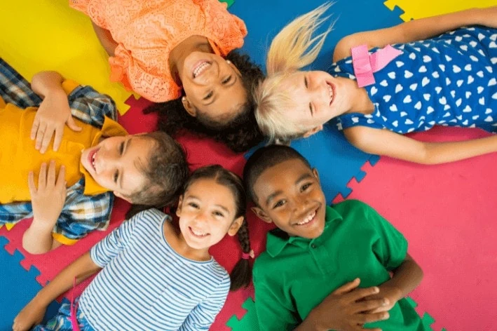 Group of kids laying on a mat with bright smiles