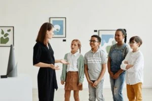 An adult giving tour around the art show to four children
