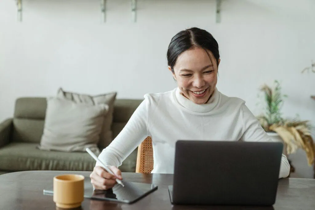Smiling Asian woman taking an onlie course seated in front of her laptop