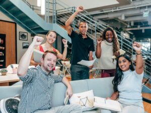 A group of workers smiling and raising their hands in cheer