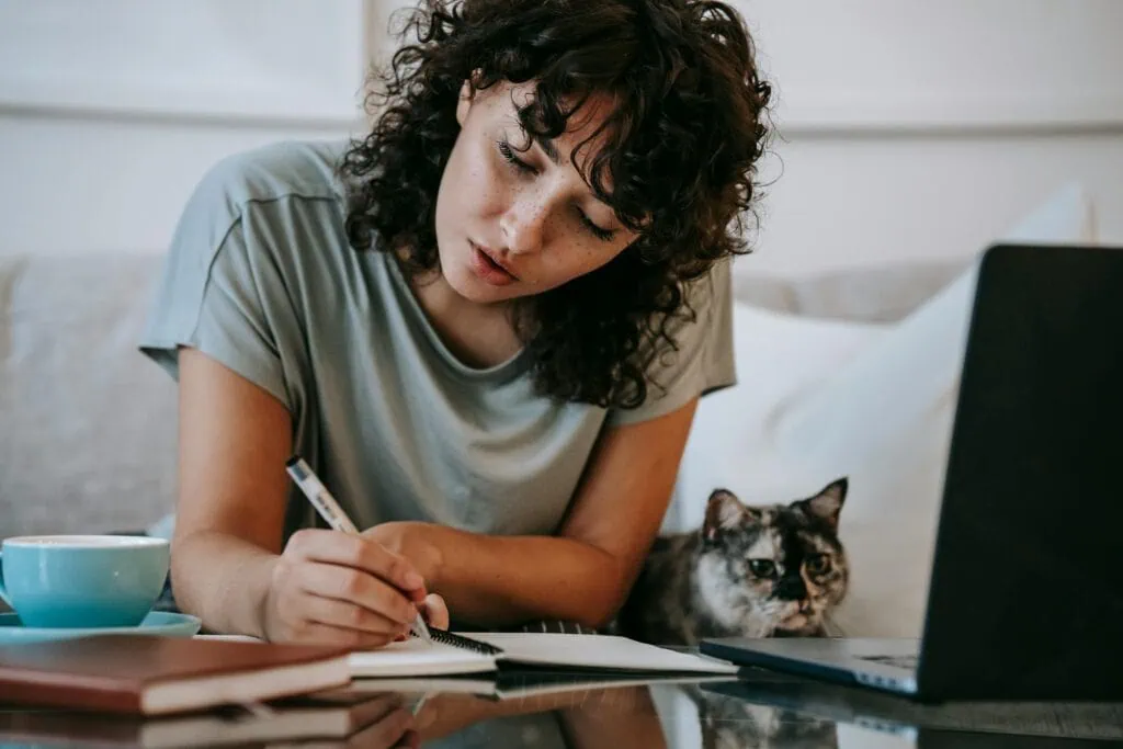 Woman taking an online course with a cat beside her