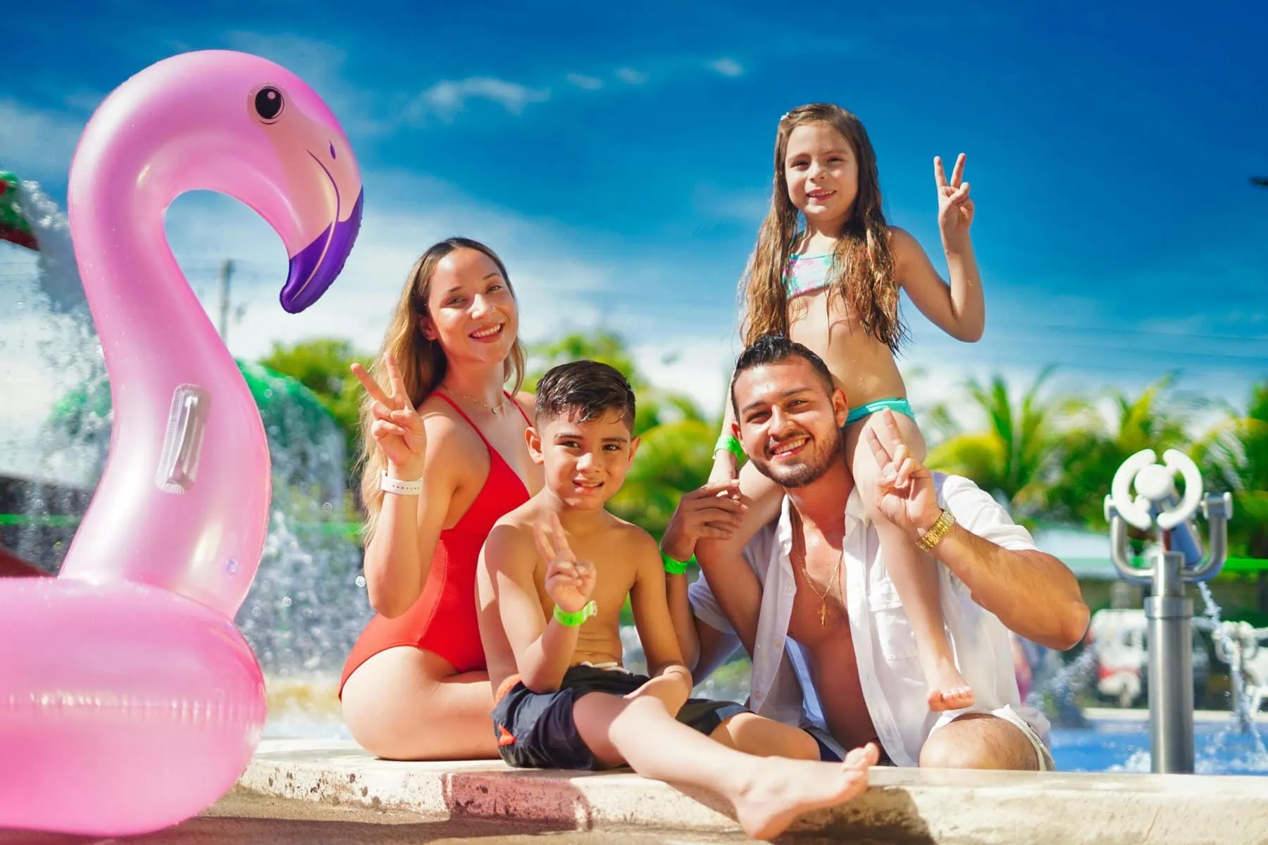 family of four in bathing suits, poolside at a resort