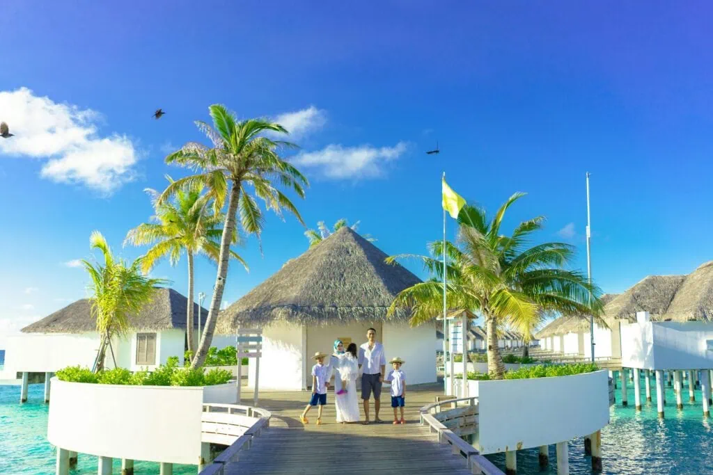 Family of 5 standing on the walkway to an overwater bungalow resort