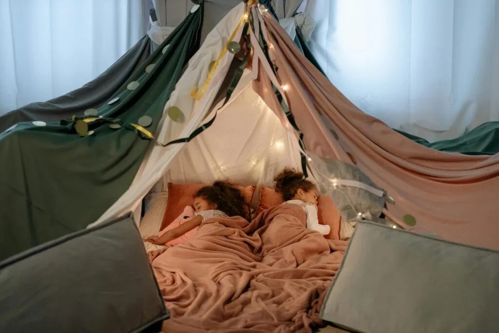 two young girls sleeping in a tent fort