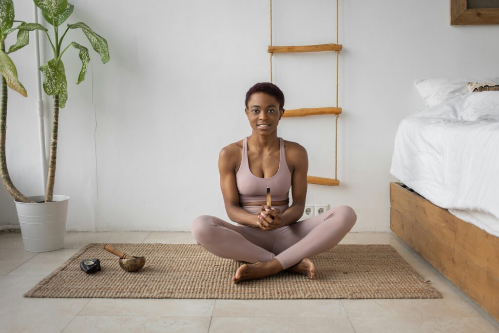 woman sitting cross legged in a comfortable corner of her bedroom