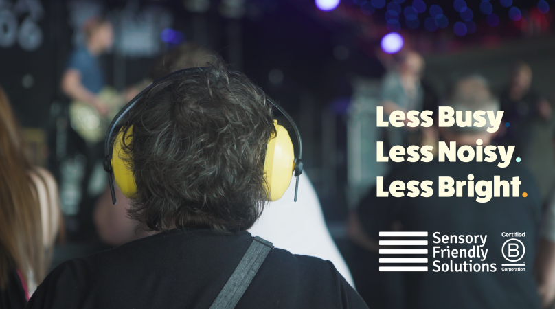 A person with short hair wearing headphones at a concert with the words less busy, less noisy, less bright and the sensory friendly solutions and bcorp logos